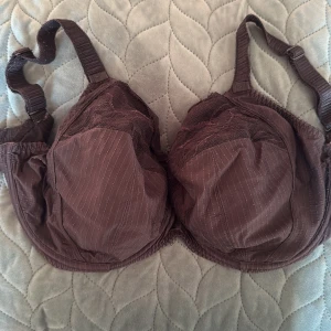 Brun spets-bh med justerbara band - Snygg brun bh med tunna ränder och spetsdetaljer upptill på kuporna. Justerbara axelband och klassisk hysk- och hakknäppning bak. Materialet känns mjukt och bekvämt, perfekt för dig som gillar både stil och komfort.