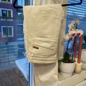 Vita chinos från NN07, storlek 32/32 - Snygga vita chinos från NN07 i klassisk rak modell. Byxorna har diskreta fickor bak med liten metallogo och är tillverkade i mjuk bomull.