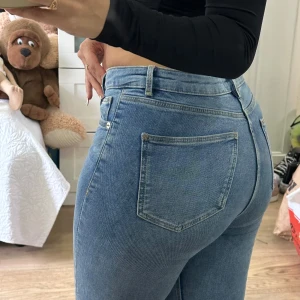 Ljusblå bootcut jeans med slits - Säljer ett par ljusblå jeans med bootcut-snitt och snygg slits nertill på benen. Jeansen är tallgirl friendly då jag är 171cm lång och de släpar i marken för mig lite 