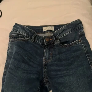 Mörkblå jeans från Lindex - Snygga mörkblå jeans från Lindex med klassisk femficksdesign och dragkedja. Jeansen har raka ben och är tillverkade i ett slitstarkt bomullsmaterial med lite stretch för extra komfort. Perfekta till sneakers eller boots.