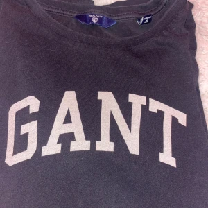 Mörkblå GANT tröja med tryck - Mörkblå långärmad från GANT i storlek XS med stort vitt GANT-tryck på bröstet. Klassisk rund hals och långa ärmar. Mjuk och skön bomull som passar perfekt till jeans eller shorts. Enkel, stilren och alltid rätt. Den är i storlek xs men den är mer som en S. Säljer då den inte används 