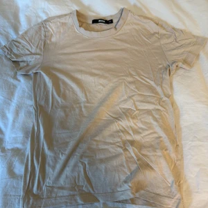 Beige basic t-shirt från Bik Bok - En enkel och stilren beige t-shirt från Bik Bok i storlek XS. Modellen har rund halsringning och korta ärmar, perfekt för en clean och chill look. Materialet är mjuk bomull som känns skönt mot huden. Passar dig som gillar minimalistisk stil.