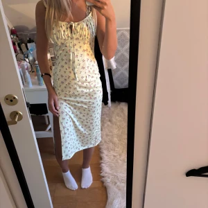 Ljusgul blommig långklänning med snörning - Supersöt långklänning i ljusgul nyans med små blommor i rosa och lila. Klänningen har smala axelband, snörning och liten öppning framtill samt en slits på sidan. Perfekt för sommarens alla tillfällen! Vet inte vart den är ifrån eller storlek men passar en xs/s/ m den är super strechig💘💘