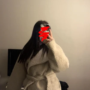 Beige teddyjacka med bälte - Supermysig beige teddyjacka med oversized passform och bälte i midjan. Jackan har stora, långa ärmar och en fluffig textur som ger en chill vibe. Perfekt för kalla dagar när du vill vara både varm och snygg. Endast använd 2-3 gånger