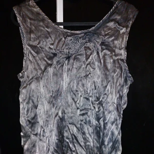 Glansig topp  - Skimmertopp från tina olsen med vacker broderad blomma 