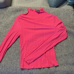 Rosa ribbad polotopp från H&M Divided - Säljer en snygg rosa polotopp från H&M Divided i storlek S. Toppen är ribbad med lång ärm och har en tight passform. Perfekt att styla med jeans eller kjol för en cool look. Hög hals och lätt vågig kant nedtill ger extra detalj.