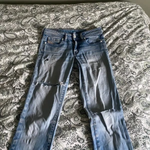 Ljusblå slitna jeans från Diesel Industry  - Ljusblå jeans från Diesel Industry med klassisk femficksdesign och slitna detaljer på benen. Jeansen har raka ben och tydliga slitningar och hål på framsidan för en riktigt avslappnad och trendig look. Perfekta för dig som gillar en streetstyle vibe.