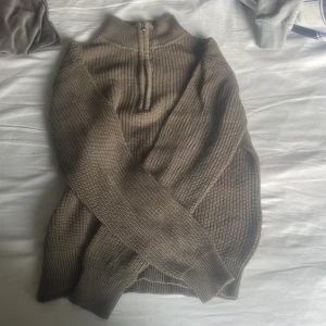  stickad half zip tröja - Säljer en beige stickad tröja med half zip och hög krage. Tröjan har långärmad modell och grovstickad struktur som ger en chill och avslappnad vibe. Perfekt för lager-på-lager och funkar till både jeans och mjukis.