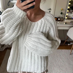 Vit stickad tröja med breda ärmar - Mysig vit stickad tröja med breda, långa ärmar och rund halsringning. Tröjan har ett grovt ribbat mönster och är perfekt för kyligare dagar. Passformen är loose och den är enkel att styla till olika outfits.