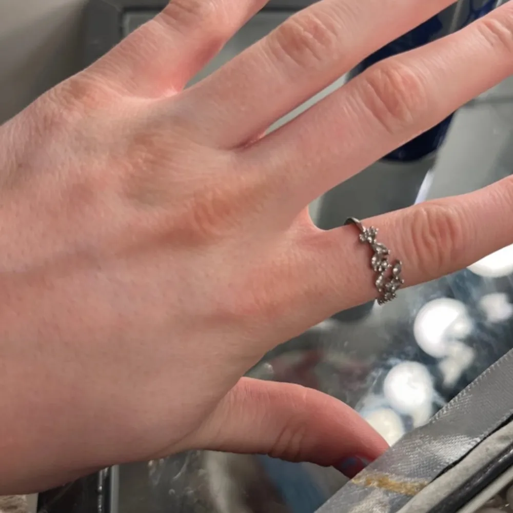 Säljer en snygg silverring med flera små blommor och gnistrande stenar. Ringen har en unik design där blommorna sitter tätt ihop och ger ett elegant intryck. Perfekt för dig som vill ha något extra till din stil.. Asusteet.