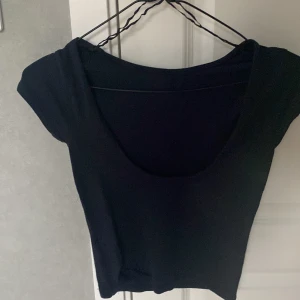Svart croppad topp från Gina Tricot - Aldrig andvänt!!En svart croppad topp från Gina Tricot med korta ärmar och rundad halsringning. Enkel och stilren design som passar till många olika outfits. Perfekt för dig som gillar en basic men trendig look.