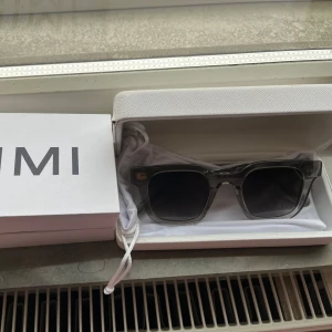 Grå transparenta solglasögon från chimi - Snygga solglasögon med transparent grå båge och mörka glas. Rektangulär form och stilren design, perfekta för att lyfta din look. Kommer i originalfodral.