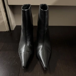 Svarta boots med spetsig tå och klack - Säljer ett par svarta boots i skinn med spetsig tå och smal klack. Använt 1 gång