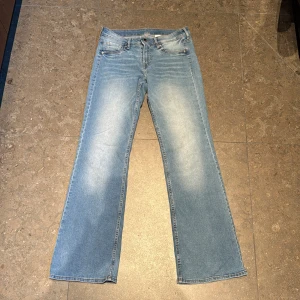 Bootcut jeans i ljusblå denim - Säljer ett par ljusblå bootcut jeans med låg midja. Klassisk femficksmodell i denim med lätt slitning framtill. Mjukt denimtyg med mycket stretch.  stl 38 men passar även en lite större 36:a