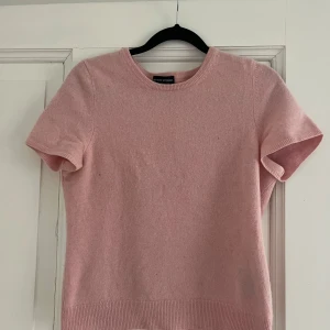 Ljusrosa kashmirtröja  - Supermjuk ljusrosa tröja i 100% kashmir T-shirt . Klassisk modell med korta ärmar och rund halsringning. Passar en Xs. 