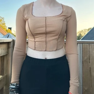 Beige långärmad topp - Trendig beige croppad topp från SHEIN med lång ärm och fyrkantig ringning. Toppen är ribbad och har en figurnära passform som framhäver siluetten. Perfekt att styla med höga byxor eller kjol.