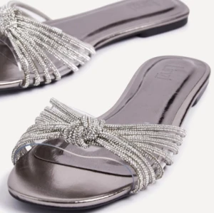 Silvriga sandaler med glitter  - Säljer ett par silvriga sandaler med öppen tå. Helt nya och oanvända!