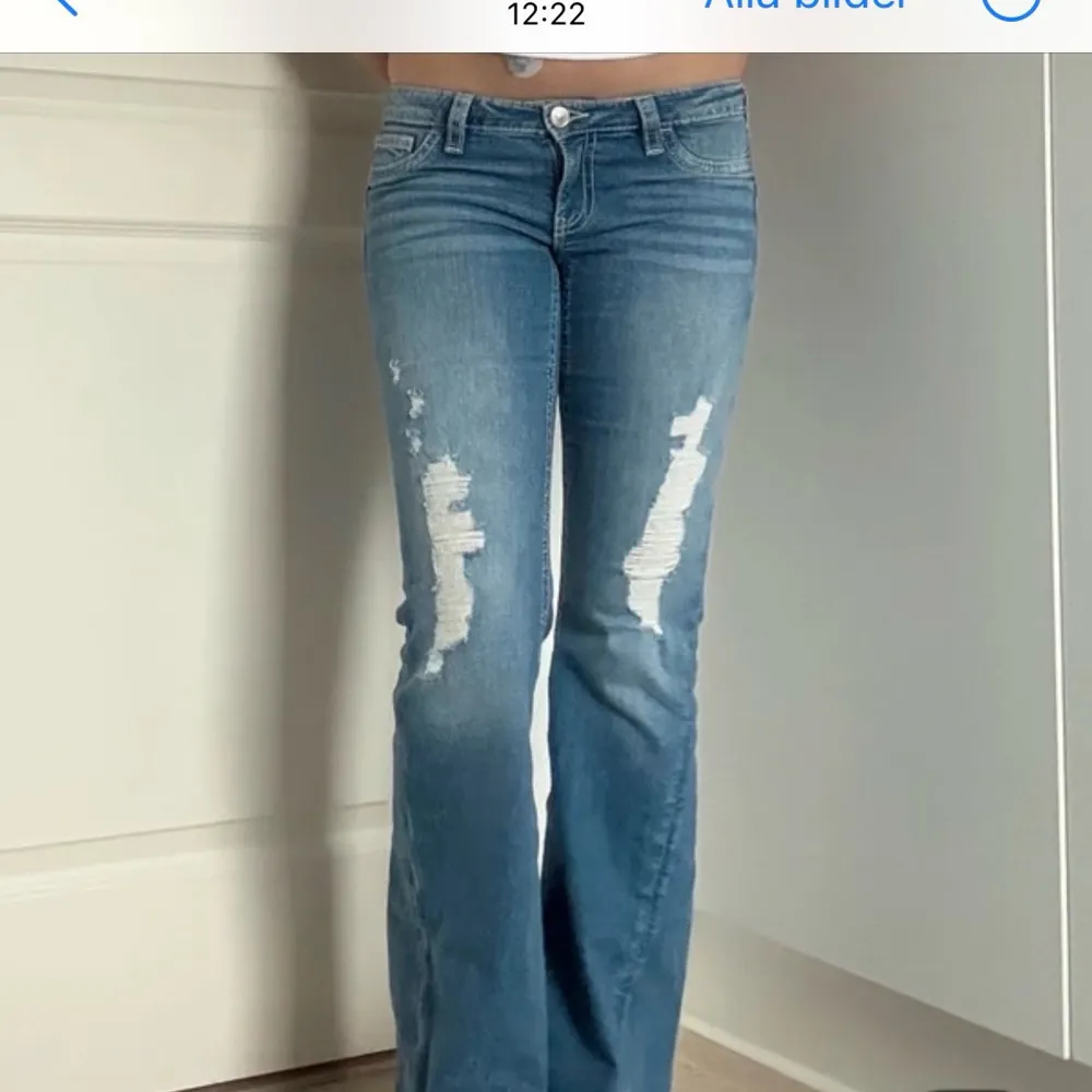 Säljer ett par blå bootcut jeans med slitna detaljer på benen och snygga bakfickor med lock. Jeansen har låg midja och klassisk femficksdesign. Perfekta för en avslappnad och trendig look. Från Ginas 14+ kollektion och är slutsålda. Dem är helt NYA med prislappen kvar!  Jeansen är storlek M men passar även S. Lämna gärna prisförslag och skriv vid minsta fråga 💞. Farkut & Housut.