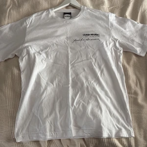 Vit Colmar Originals t-shirt - Vit t-shirt från Colmar Originals x Yosuke Aizawa, Revolution Collection. Klassisk passform med rund hals och tryck på bröstet. Stilren och enkel design, perfekt för dig som gillar cleana plagg med diskret branding.