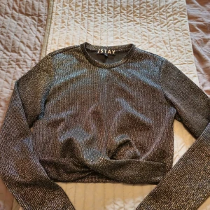 Glittrig silvertröja från Stay - Säljer en glittrig långärmad tröja från Stay i silver med ribbad struktur. Tröjan har rund halsringning och är i ett stretchigt material som sitter snyggt på kroppen. Perfekt för dig som vill sticka ut lite extra med en cool look.
