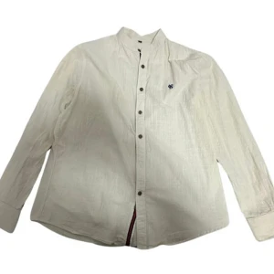 Khaki  linneskjorta  - Snygg khaki skjorta i linne med ståkrage och knappar hela vägen framtill. Långärmad modell med minimalistisk design och liten broderad detalj på bröstet. Perfekt för dig som gillar en clean och stilren look.