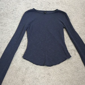 Mörkblå långärmad topp- Dazy - Säljer en mörkblå långärmad topp från Dazy i storlek S. Tröjan är ribbad med smal passform och har en lätt vågig nederkant. Materialet är mjukt och stretchigt- väldigt enkel och bekväm.