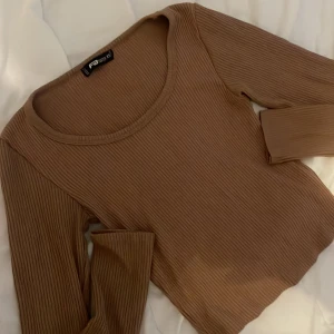 Ribbad brun långärmad tröja FB Sister - Säljer en ribbad brun långärmad tröja från FB Sister i storlek XS. Tröjan har en rund halsringning och är i ett stretchigt, mjukt material som sitter snyggt på kroppen. Perfekt att styla med jeans eller kjol för en chill look.