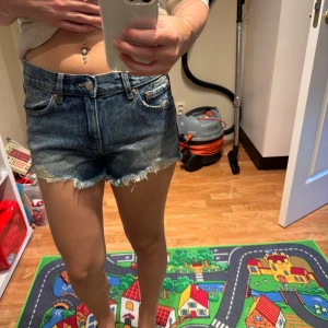 Blå jeansshorts med fransig kant - Snygga blå jeansshorts med fransig kant och fickor. Shortsen har låg midja och en avslappnad passform. Perfekta för sommardagar när du vill ha en cool och enkel look. Gillar du denim är dessa ett måste i garderoben! Aldrig använda endast testade och dragit bort prislapp