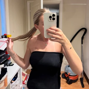 Svart ribbad tubtopp - Säljer en svart tubtopp som sitter tight och ärmlös. Perfekt för dig som gillar en enkel och stilren look. Toppen är ribbad och har en klassisk, rak passform som funkar till många olika outfits.