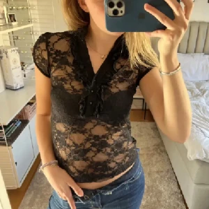 Svart spetsblus med volangdetalj - Säljer en svart, transparent spetsblus med korta ärmar och volangdetaljer. Nyskick. Storlek S. Lappar borttagna. Från Zara. 