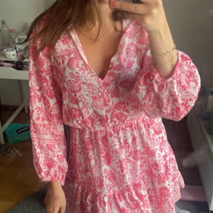 Rosa och vit blommig kortklänning - Supersöt kortklänning i rosa och vitt med blommigt mönster. Klänningen har v-ringning, långa puffärmar och volangdetaljer i kjolen. Från zara. Från förra året men inte hunnit använda 