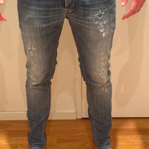 Dondup Jeans  - Säljer ett par blåa dondup jeans med slitna detaljer och tvättad look. Jeansen har smal passform, klassiska fem fickor och knappgylf. Perfekta för dig som gillar en modern och avslappnad stil. Nypris 4000. Vid eventuella frågor är det bara att höra av er! 