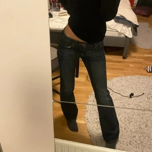 EDC mörkblå jeans bootcut - Mörkblå EDC jeans med klassisk bootcut-passform och låg midja. Jeansen har snygga kontrastsömmar och fem fickor. Tillverkade i slitstarkt denim med en tidlös look som passar till allt. Perfekta om du gillar en retro vibe och vill ha ett par jeans som sitter snyggt på höften.