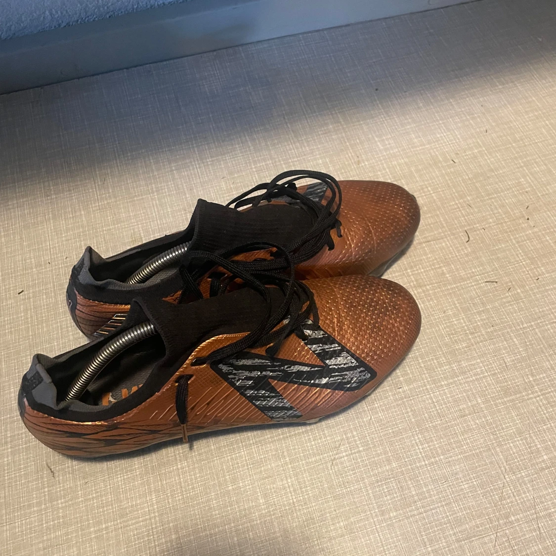 Bronsfärgade fotbollsskor med snörning