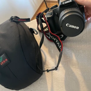 Canon EOS 1000D Digital systemkamera - Canon EOS  1000D Digital systemkamera med 18-55mm objektiv och originalväska. Perfekt för dig som vill ta din fotografering till nästa nivå, oavsett om du är nybörjare eller vill utveckla din kreativitet. Enkel att använda och smidig att ta med på äventyr.