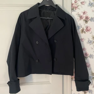 Svart croppad trenchcoat  - Jättefin jacka i mycket bra skick. Endast en lös tråd jag klipper bort när den säljs. 