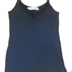 Svart spetslinne - Svart linne med spets från nowOn med smala, justerbara axelband och v-ringning dekorerad med fin spets. Perfekt nu i sommar!