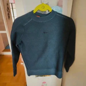 Mörkblå sweatshirt från BOSS - En stilren mörkblå sweatshirt från BOSS med diskret logga på bröstet. Tröjan har rund halsringning,. Perfekt för dig som gillar en clean och enkel look.