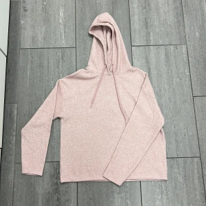 Ljusrosa hoodie från Amisu - Mysig ljusrosa hoodie från Amisu i mjukt stickat material. Tröjan har huva med snörning och långa ärmar. Perfekt för chill dagar och enkel att matcha med jeans eller leggings.