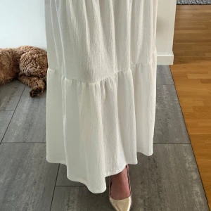 Vit långklänning med volang🤍 - Superfin vit långklänning med volangdetaljer och lätt struktur i tyget. Klänningen har en luftig och flowy känsla, perfekt för sommarens alla tillfällen. Enkel men ändå elegant stil som passar dig som gillar en clean look. Köpt från Gina tricot och aldrig använd🤍