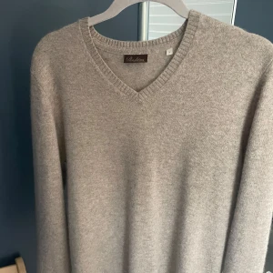 Beige kashmirtröja med v-ringning från Stenströms - Mjuk och lyxig beige kashmirtröja från Stenströms med v-ringad hals. Klassisk modell med lång ärm och ribbade muddar. Perfekt för lager-på-lager under kyliga dagar. Har ett litet hål i armhålan som inte syns när man väl har på den. Ny pris ca 4000