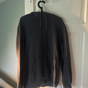 Mörkgrå hoodie från Divided - En enkel och stilren mörkgrå hoodie från Divided. Tröjan har huva med dragsko och en stor magficka framtill. Perfekt för dig som gillar en avslappnad och bekväm stil.