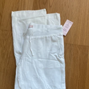 Vita linnebyxor från Nelly - Säljer ett par snygga oanvända vita linnebyxor från Nelly. Byxorna har raka ben och stora fickor framtill. 