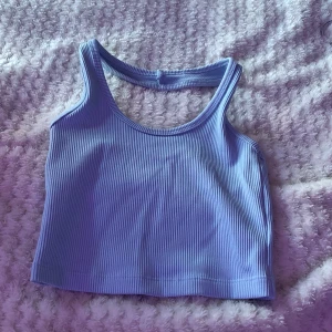 Ljusblå ribbad linnetopp från H&M - Säljer en ljusblå ribbad linnetopp från H&M. Toppen har band som går runt vid nacken med breda axelband och rund halsringning. Perfekt att styla till jeans eller kjol för en avslappnad look.