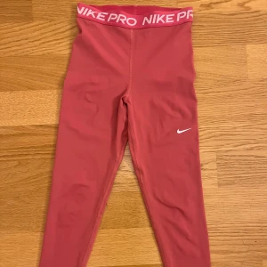 Rosa Nike Pro tights - Rosa tights från Nike. Använda några gånger och har tecken på användning. De har en liten fläck och även en liten defekt vid en söm men det är inget som påverkar användningen (se bild). Sista bilden är tagen med blixt för att bättre kunna se färgen på byxorna.