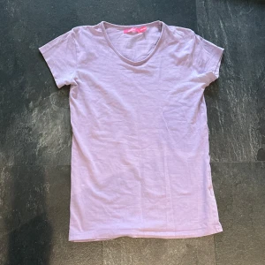 Ljuslila t-shirt från Skill - En enkel och stilren ljuslila t-shirt från Skill med v-ringad hals. T-shirten är kortärmad, perfekt för vardagsbruk.