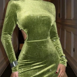 Grön sammetsklänning med cut-out - Säljer en glittrig grön sammetsklänning med lång ärm och tight passform. Klänningen har en snygg cut-out detalj i midjan och är kort i modellen. Perfekt för dig som vill sticka ut med en trendig look.