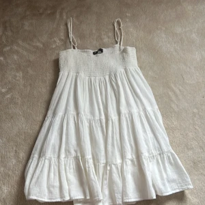 Vit somrig klänning från ZARA - Supersöt vit klänning från ZARA med  tunna axelband. Klänningen har en luftig och volangig design med flera lager.