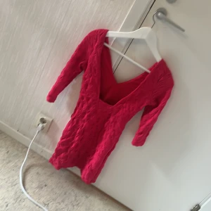Röd kort klänning från H&M - Säljer en röd kort klänning från H&M med v-ringning och trekvartsärm. Klänningen har en åtsittande passform och ett strukturerat, rynkat tyg som ger en cool effekt. Perfekt för dig som vill sticka ut med färg och form!