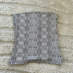 Svartvit mönstrad kuvertväska - Säljer en kuvertväska med svartvitt geometriskt mönster. Väskan har en fyrkantig form och är perfekt för att bära småsaker. Passar dig som gillar unika accessoarer med grafisk stil.